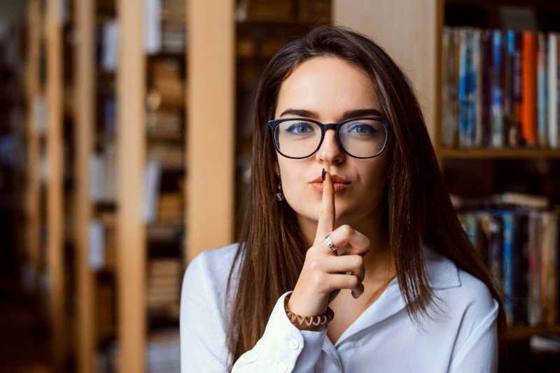 A woman making a silence gesture in a library